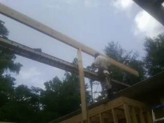 Carpenter setting a ridge beam over a new addition frame — Ice Dam Removal by Roofing Brothers in Mc Ewen