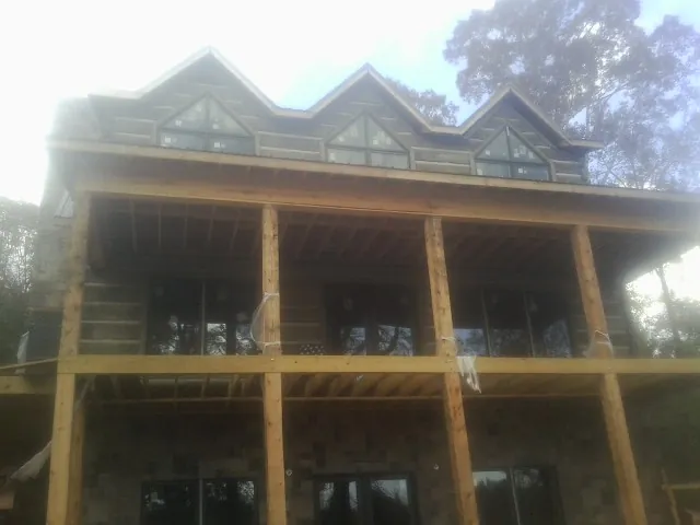Dormers and porch framing on a large log home under construction — Roof Coating work by our crew in Mc Ewen