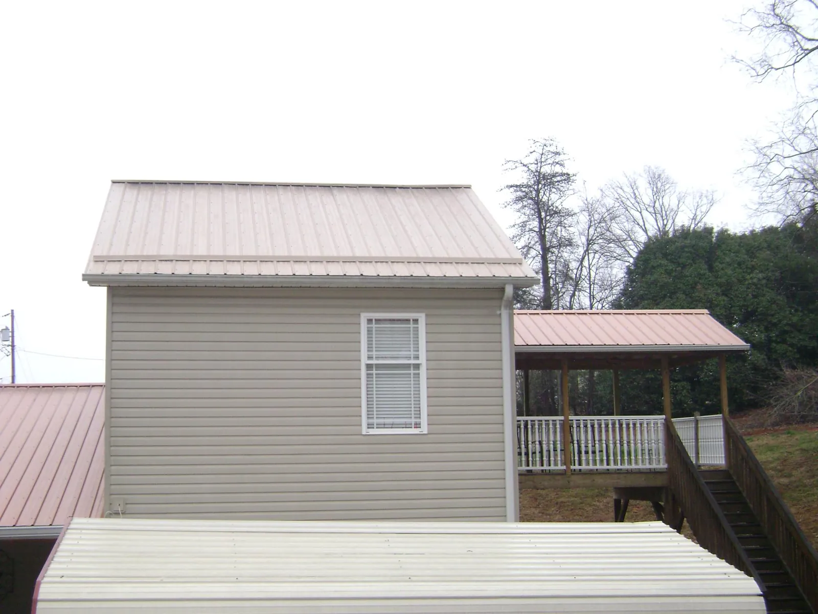Tan metal roofs on a two story addition and attached porch, from a Roof Replacement job in Mc Ewen