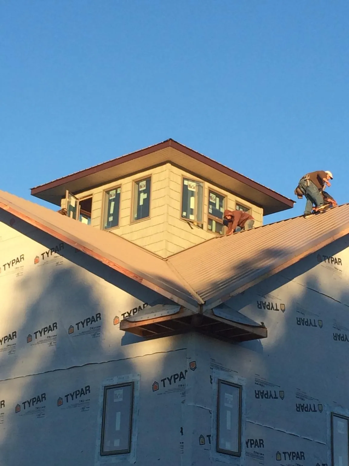 Roofers working around a rooftop cupola on a new metal roof at sunset — Roof Waterproofing in Mc Ewen by Roofing Brothers